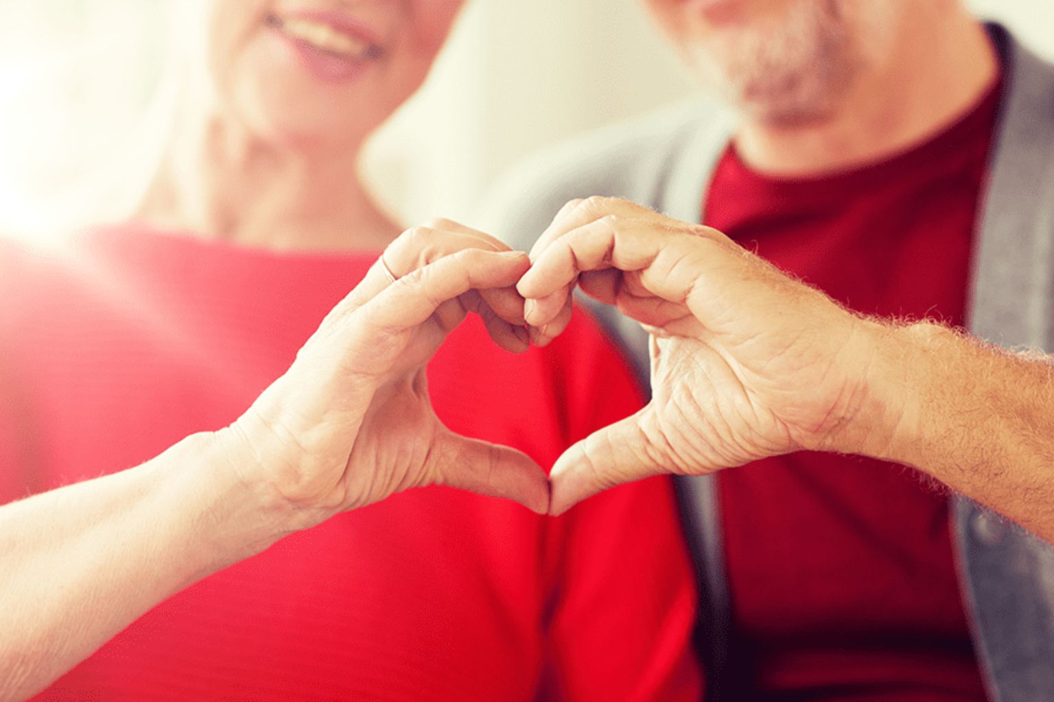 Older couple forming a heart shape with their hands