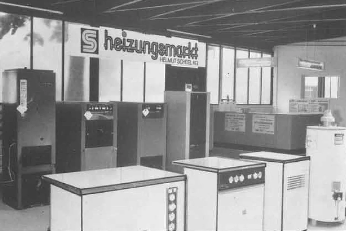 Mehrere Gasthermen (vermutlich Ausstellungshalle) und Firmenschild "heizungsmarkt Helmut Scheel" an der Decke