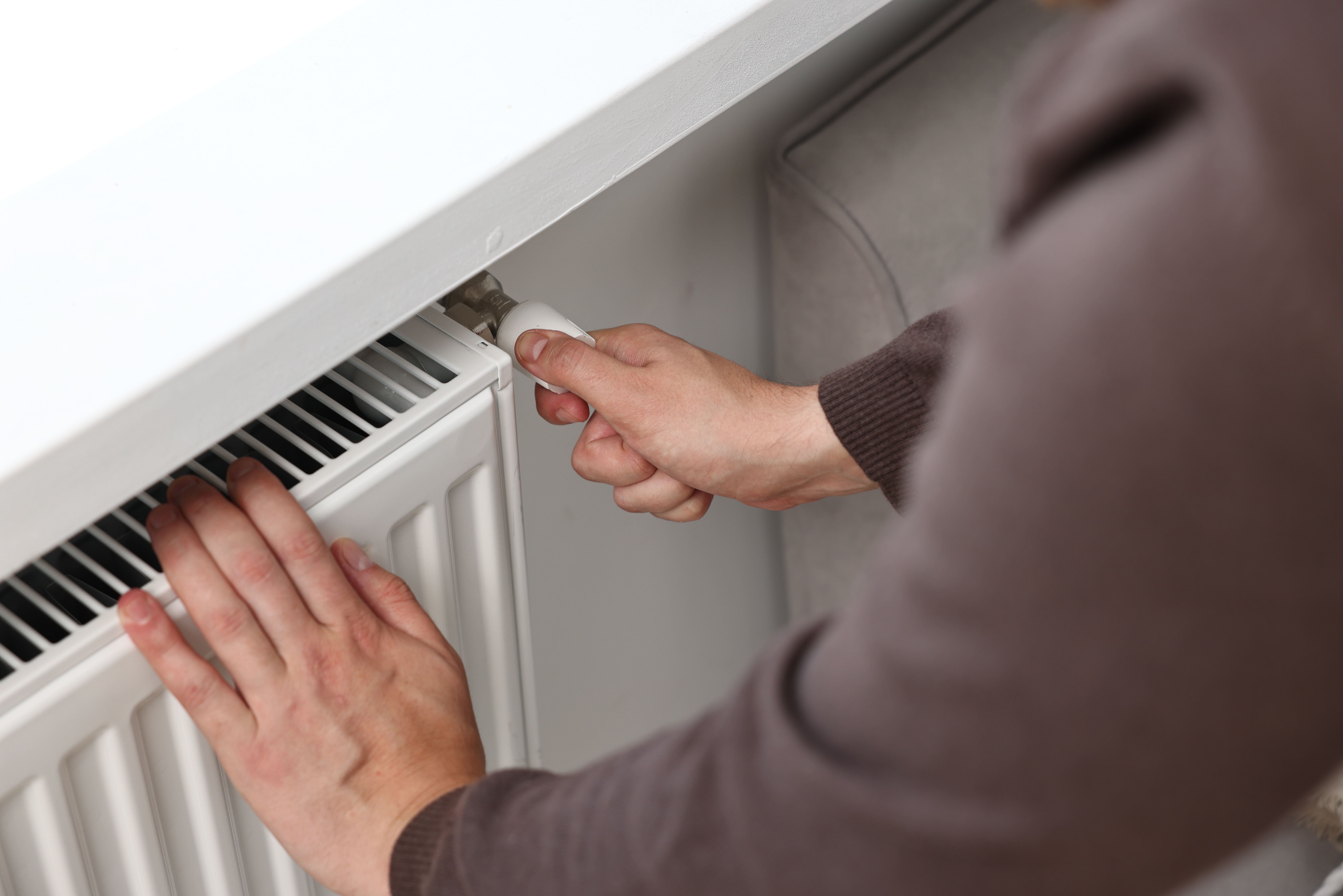 Mann stellt Temperatur am Heizkörper in den Räumen ein -Nahaufnahme