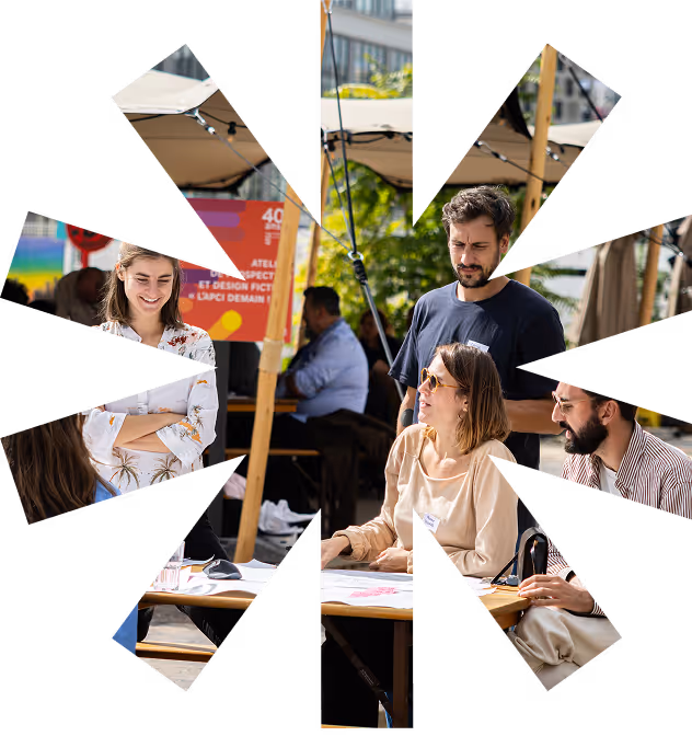 Quatre adultes discutant autour d'une table en extérieur sous un parasol lors d'un événement.