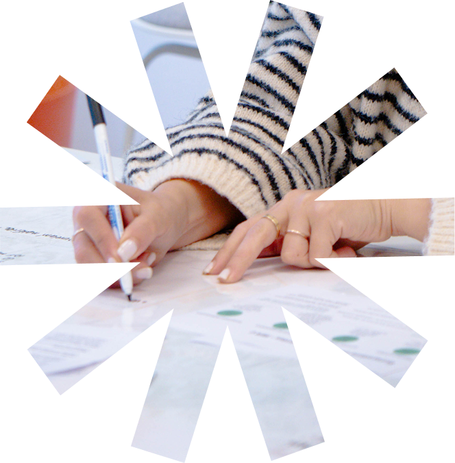 Personne écrivant avec un stylo bleu sur des documents papier sur une table.