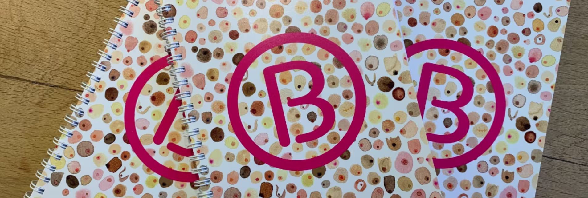 Notitieboek met kleurrijke stippen en het logo van Borstkankervereniging Nederland (BBN) met roze letters in cirkels.