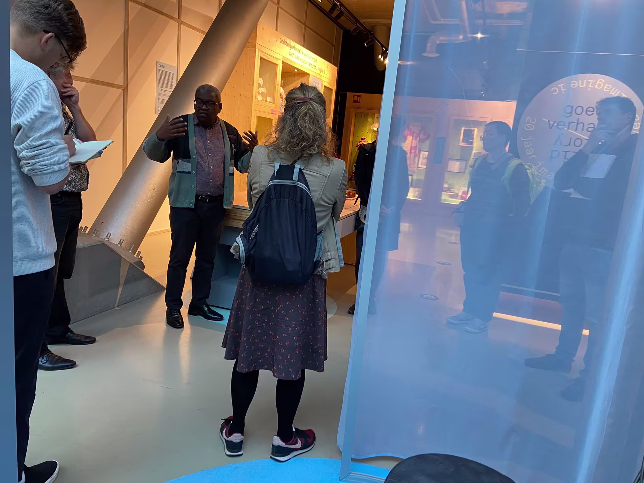 Bezoekers bekijken een interactieve expositie in een museum met blauwe verlichting en moderne displays.