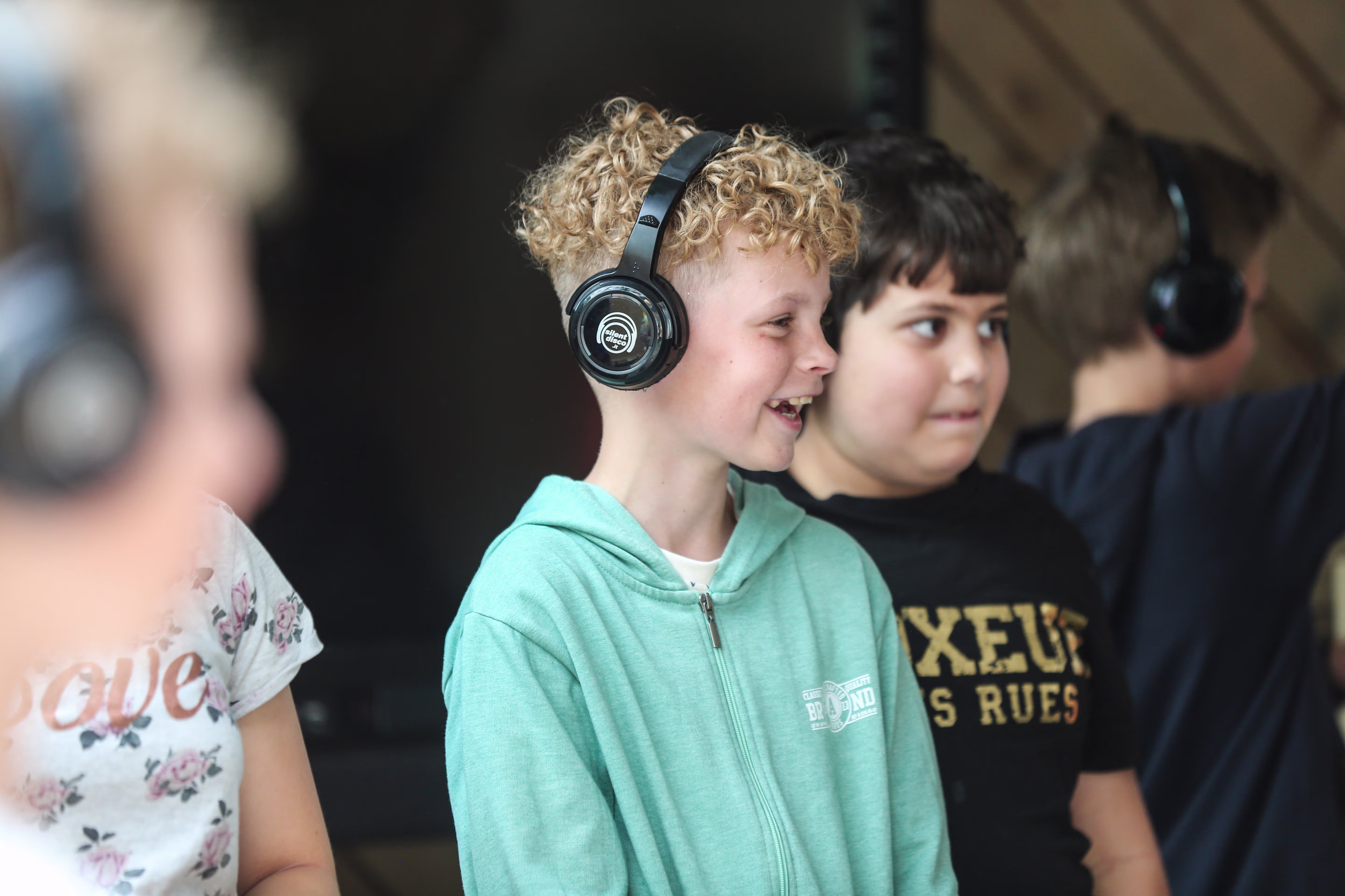 Kinderen met koptelefoons luisteren geconcentreerd naar audio, waarschijnlijk tijdens een culturele of educatieve activiteit.