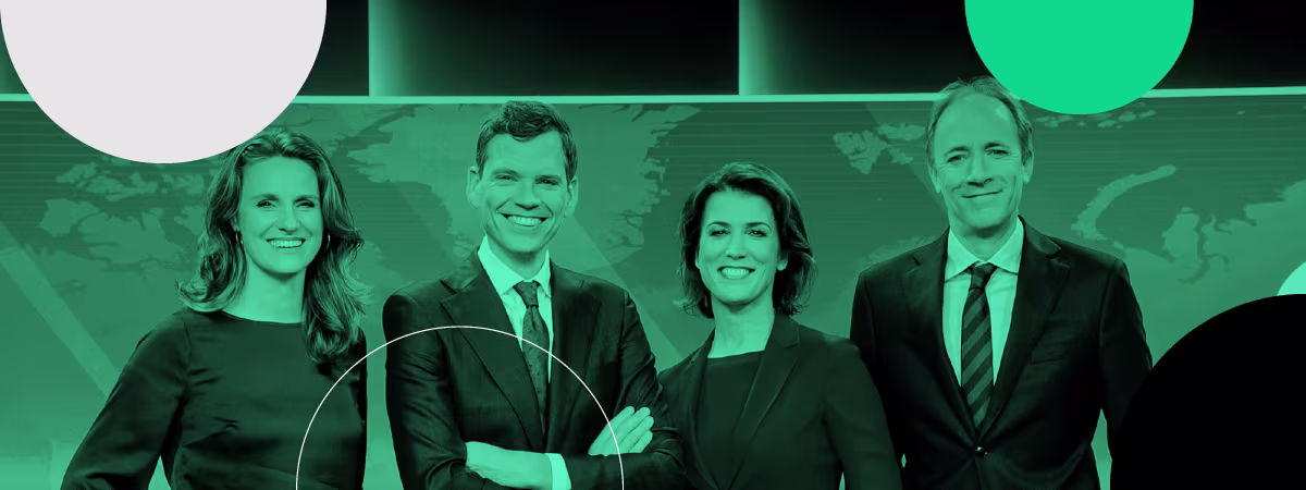 Vier professioneel geklede personen poseren glimlachend voor een groene achtergrond met wereldkaart in een tv-studio setting.