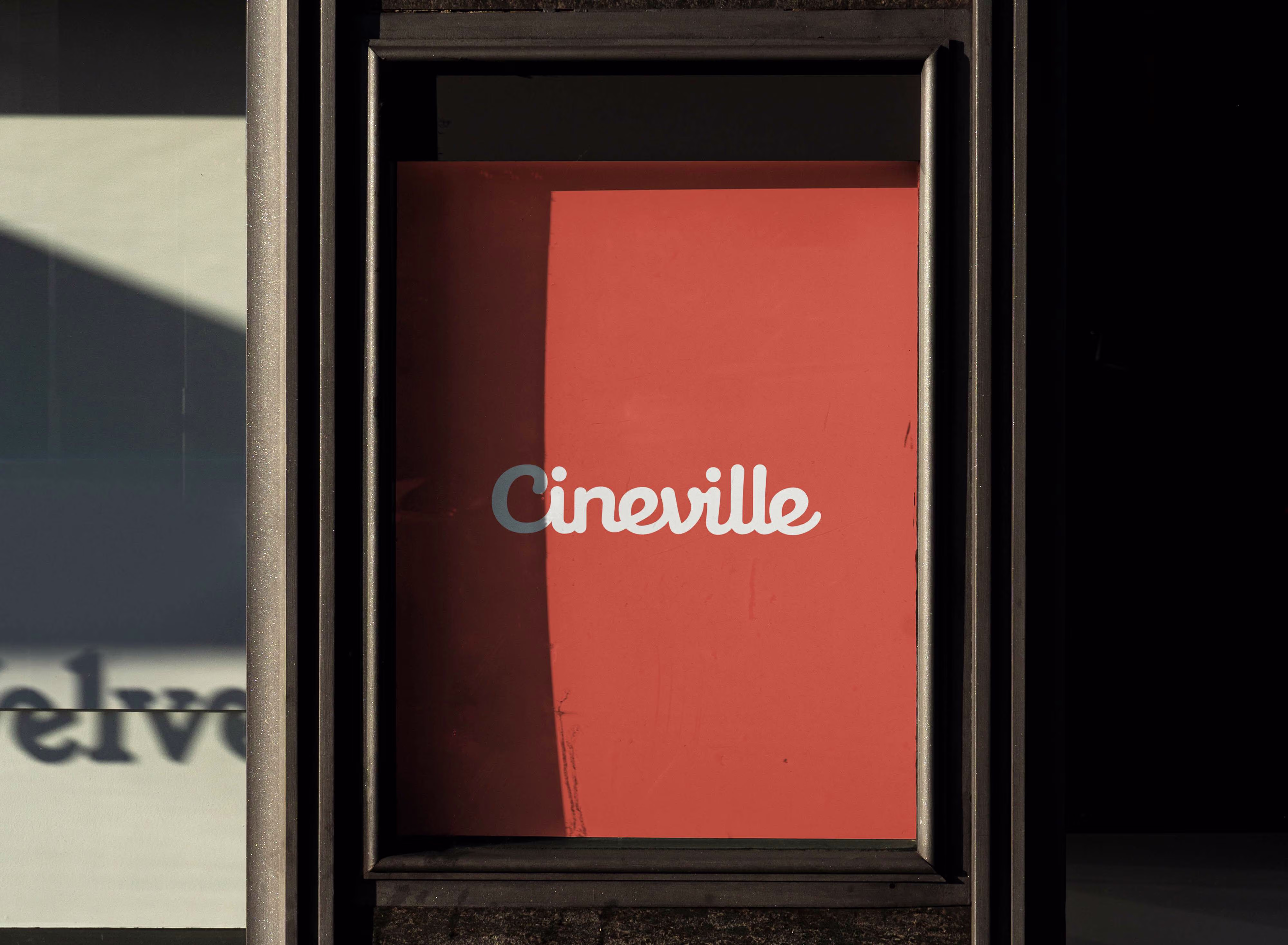 Een oranje poster met witte letters "Cineville" in een zwart frame aan de muur van een gebouw.