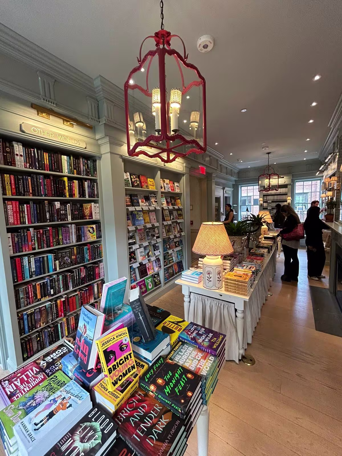 Een elegante boekwinkel met volle boekenplanken, een rode lantaarn aan het plafond en klanten die rondkijken tussen de boeken.