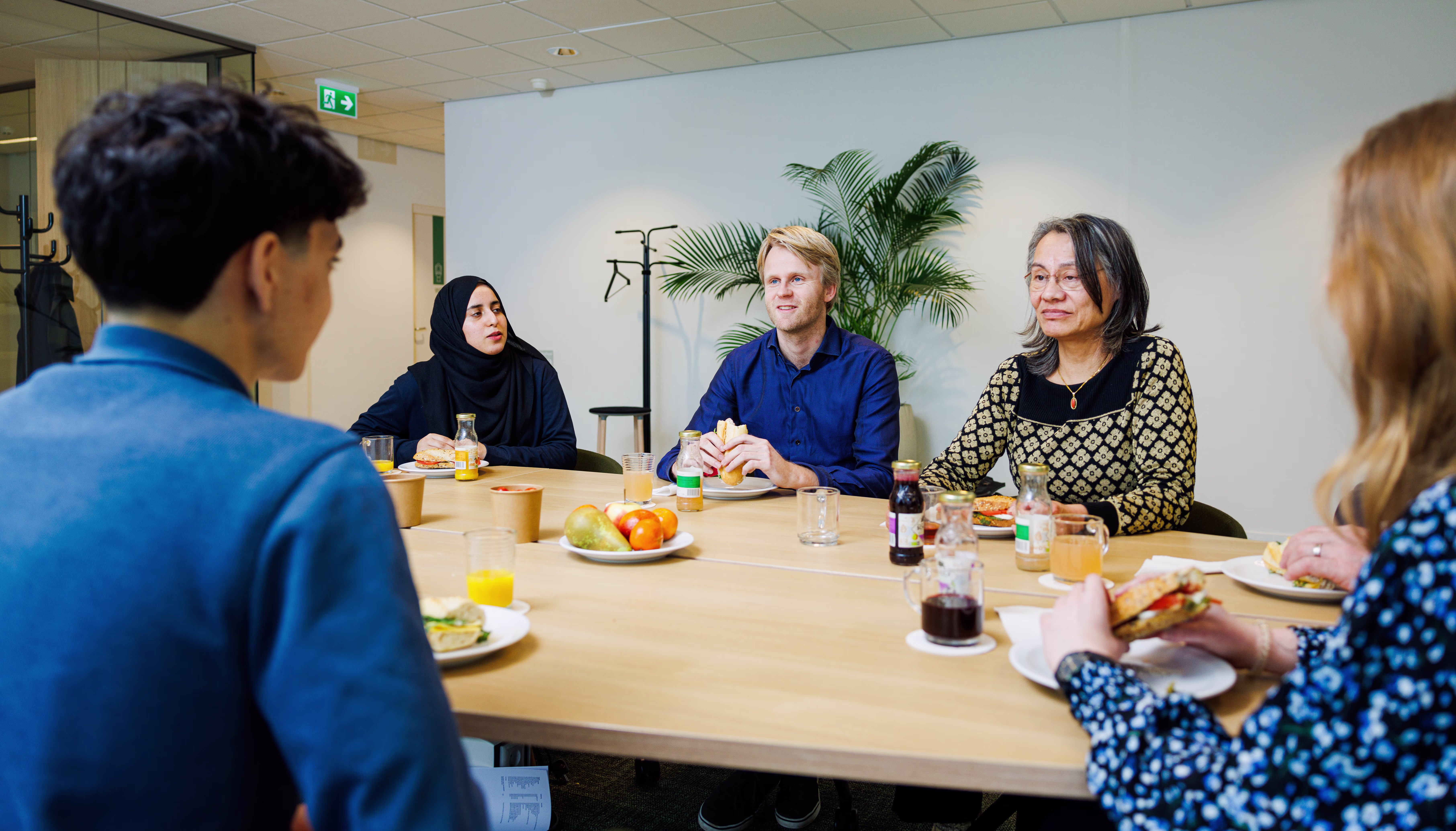 Collega's van Arkin zitten samen aan tafel tijdens een gezellige lunch of koffiepauze op de werkplek.