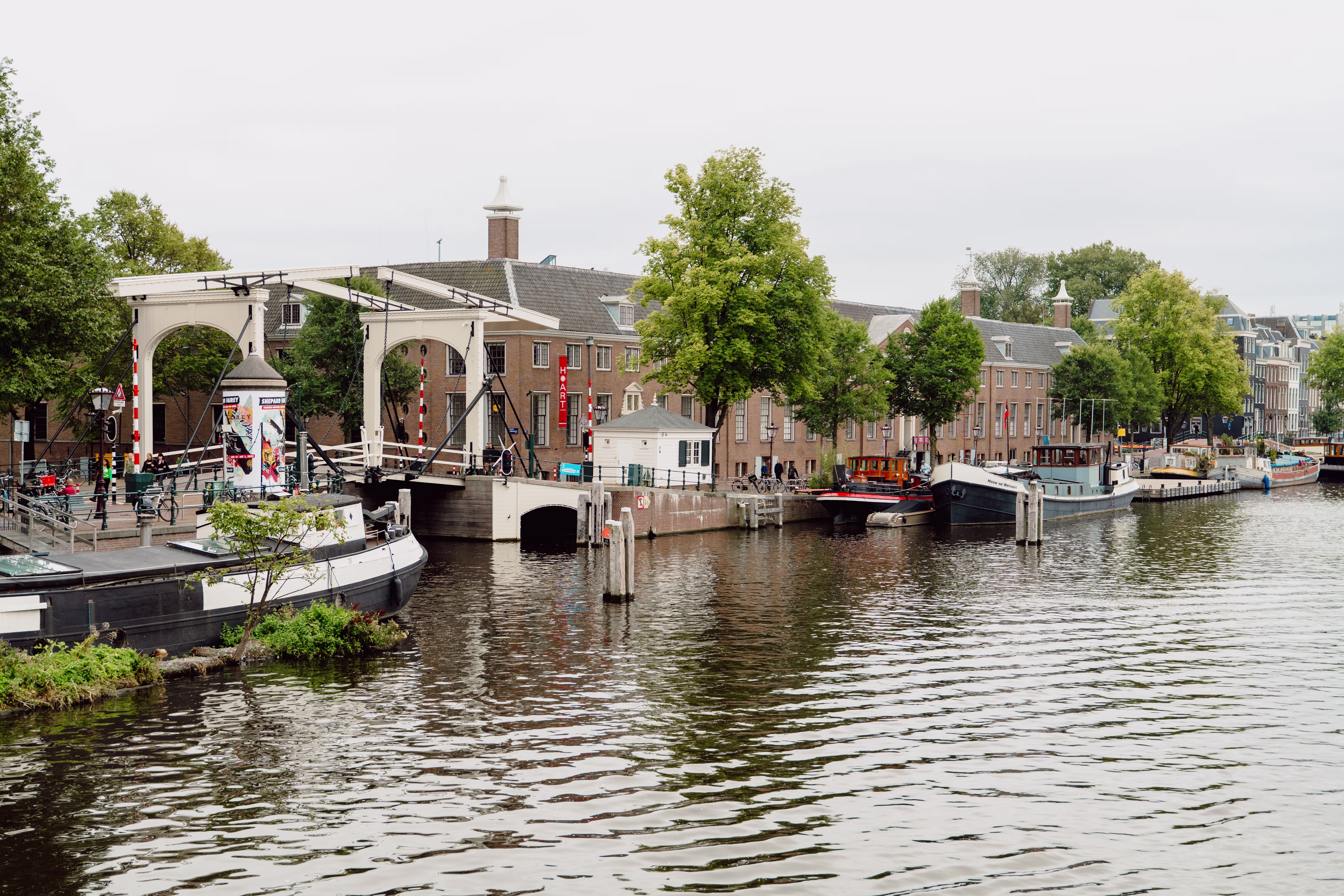 Een historische ophaalbrug over een gracht met boten en bakstenen gebouwen in een Nederlandse stad.