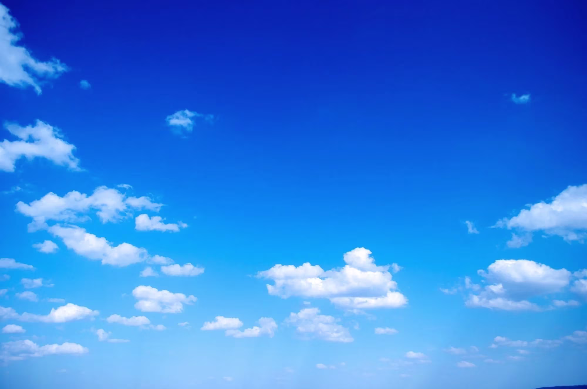 Heldere blauwe lucht met witte wolkjes op een zonnige dag.