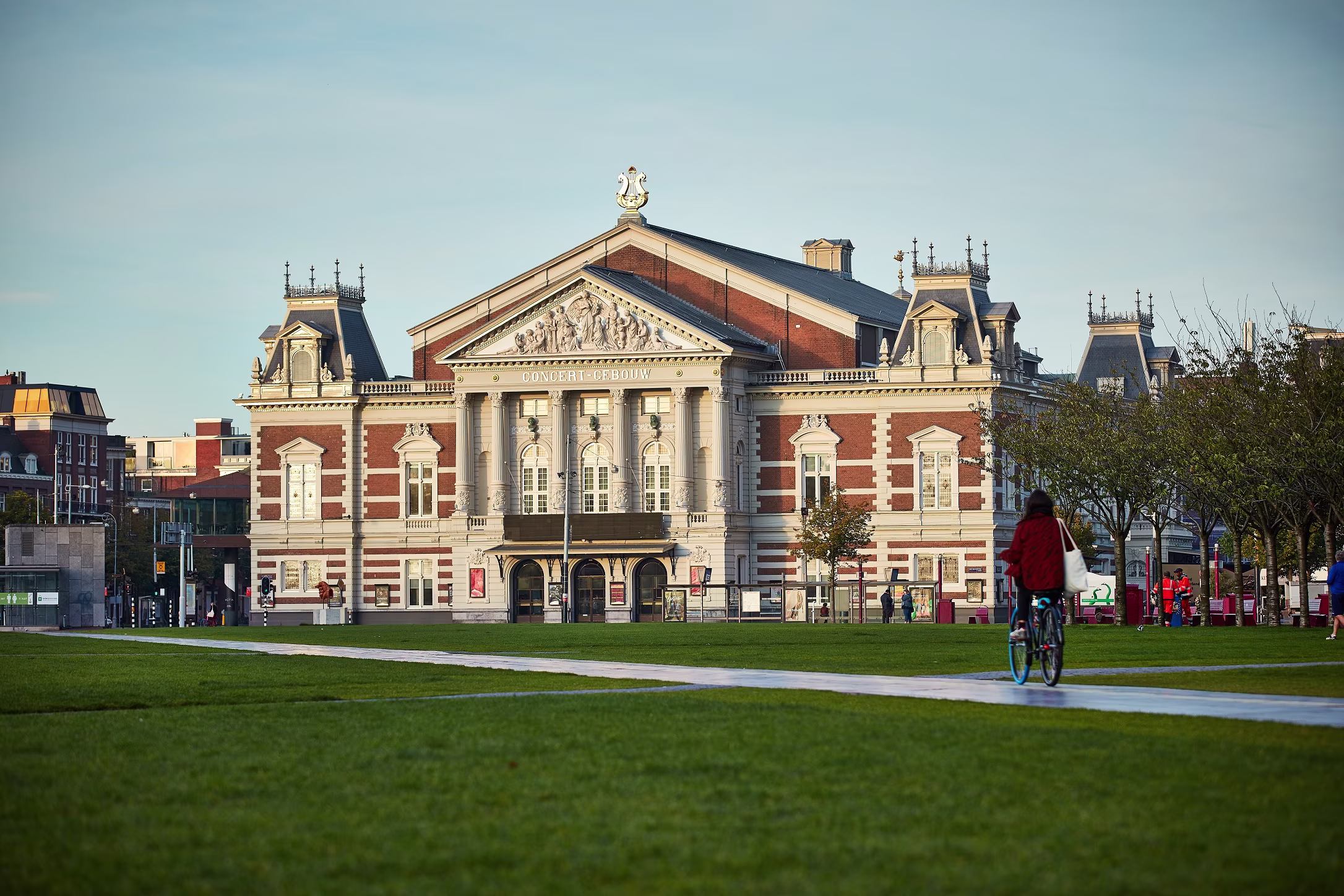 Het Koninklijk Concertgebouw in Amsterdam met zijn kenmerkende rode bakstenen gevel en klassieke architectuur, omgeven door groen.