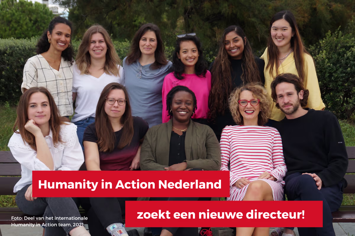Groepsfoto van elf jonge professionals van Humanity in Action Nederland, zittend en staand op een bankje in een park.