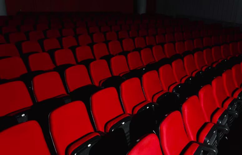 Lege rode bioscoopstoelen in rijen opgesteld in een donkere filmzaal.