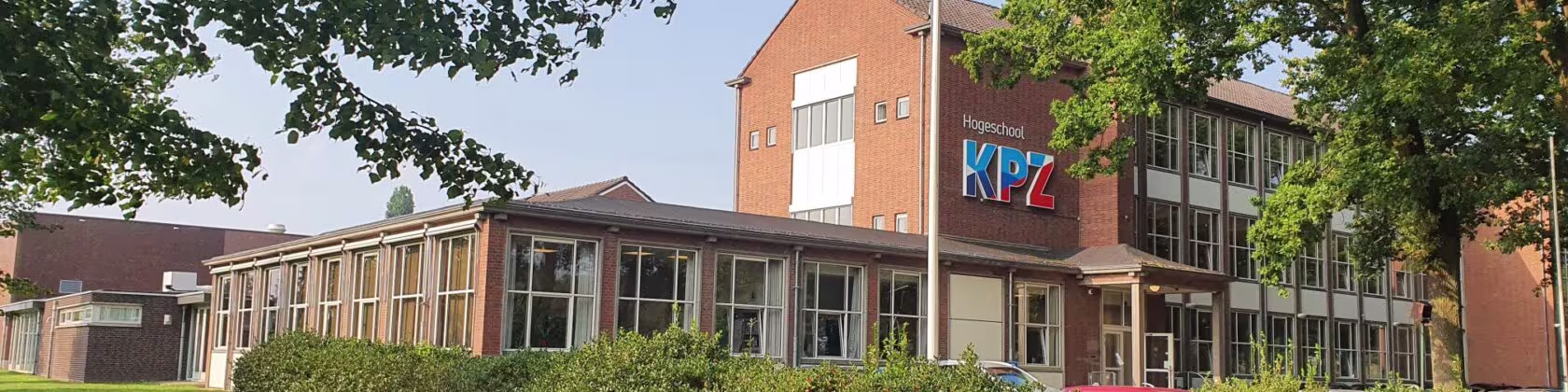 Moderne ziekenhuisgebouw met rode bakstenen gevel en grote ramen, omgeven door groen en bomen.