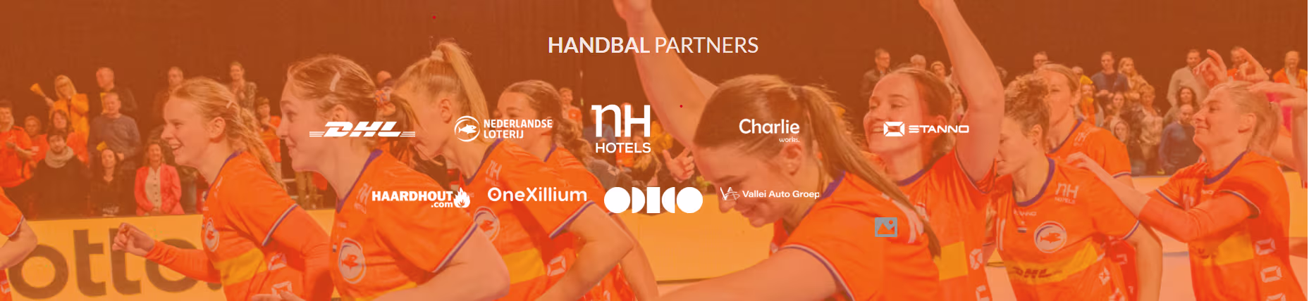 Nederlandse handbalsters in oranje tenues juichen na een overwinning, met sponsor- en partnerlogo's zichtbaar.