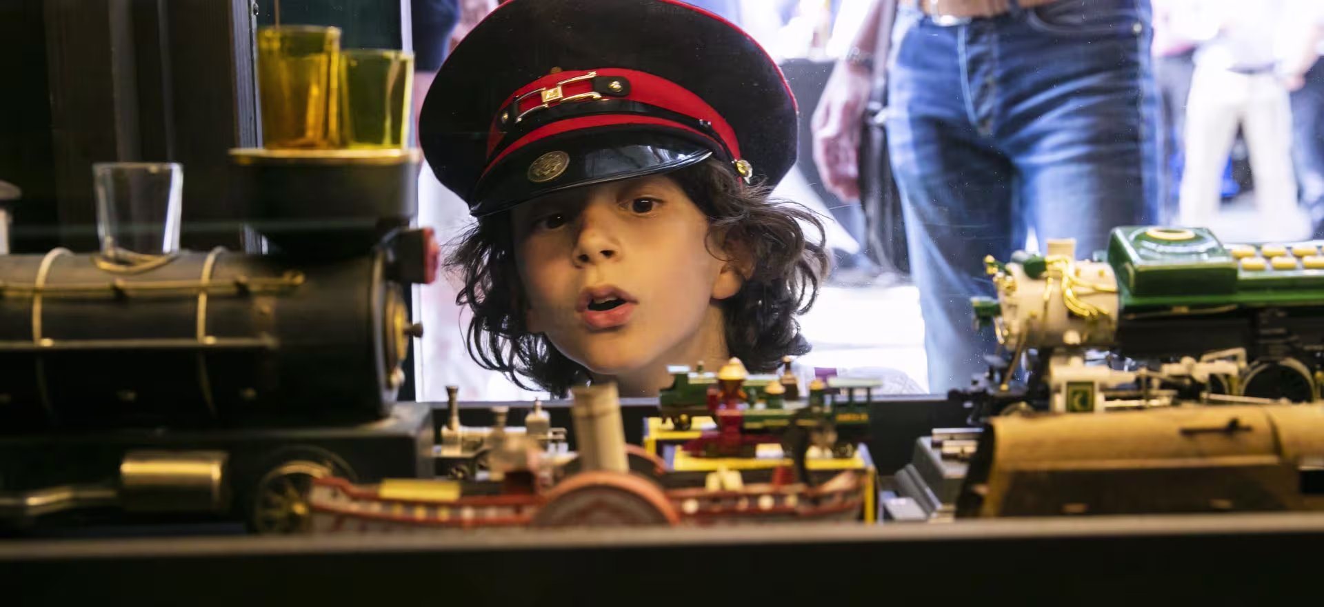 Kind met conducteurspet kijkt gefascineerd naar modeltreinen in het Spoorwegmuseum.