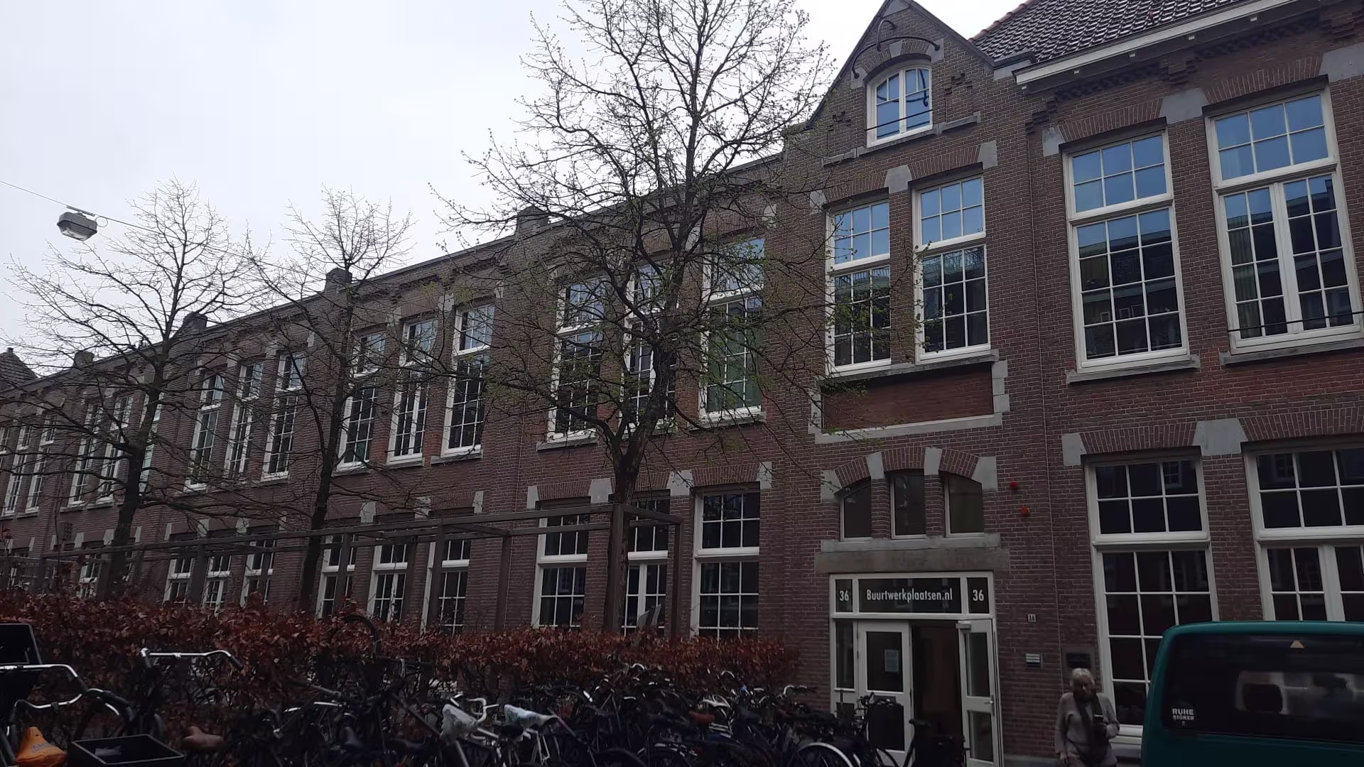 Bakstenen gebouw met grote ramen en fietsen ervoor, kenmerkend voor Nederlandse zorginstelling Buurt Werkplaatsen.