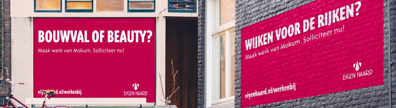 Roze reclameborden van Eigen Haard met teksten "Bouwval of beauty?" en "Wonen voor de rijken?" aan gevels van gebouwen.