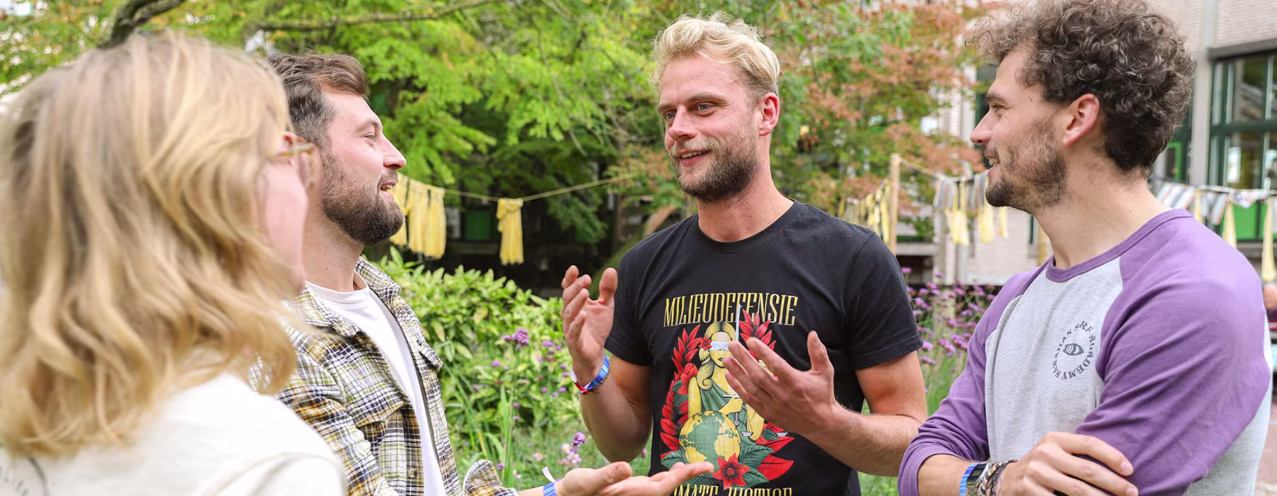 Vier collega's staan buiten te praten in een groene tuin bij het kantoor van Milieudefensie.