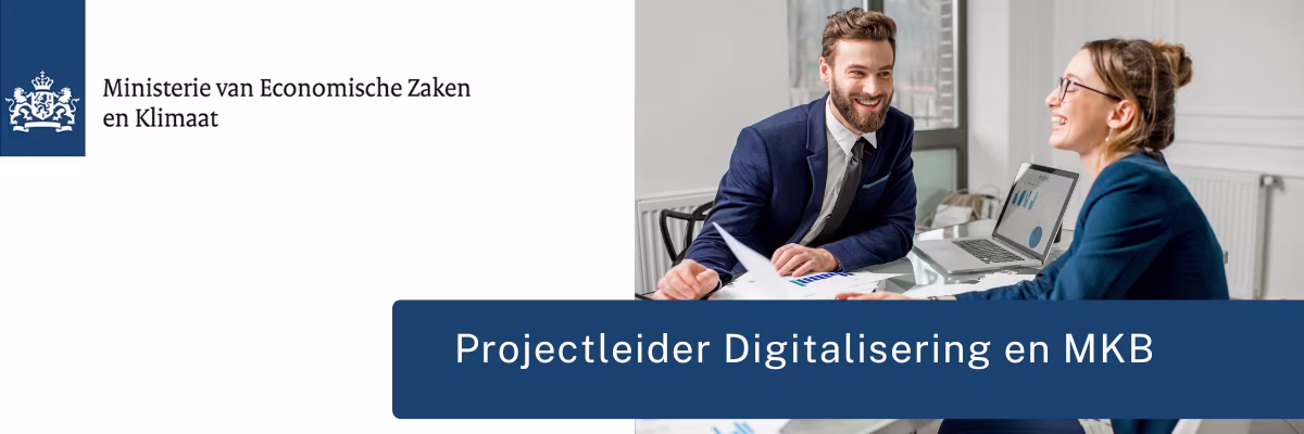 Twee collega's in pak bespreken werk aan bureau met laptop, lachend in modern kantoor van Ministerie EZK.
