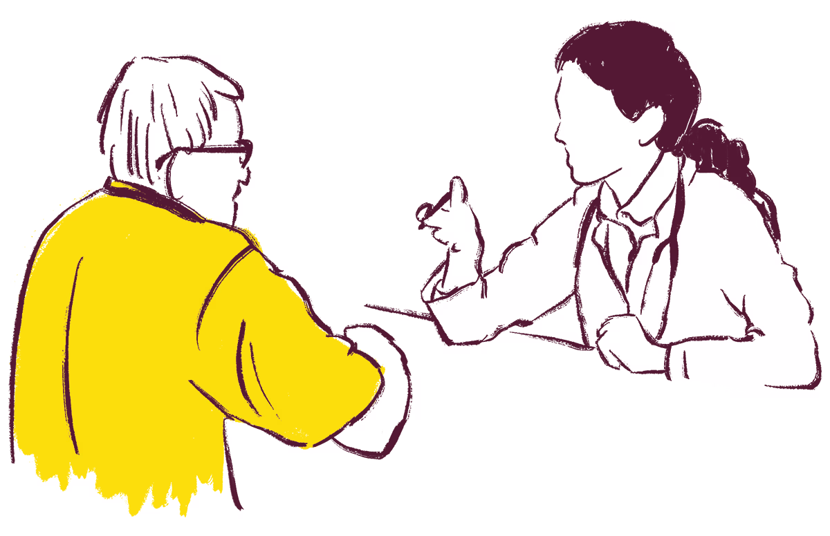 Twee personen zitten tegenover elkaar aan een tafel in gesprek, één draagt een gele trui.