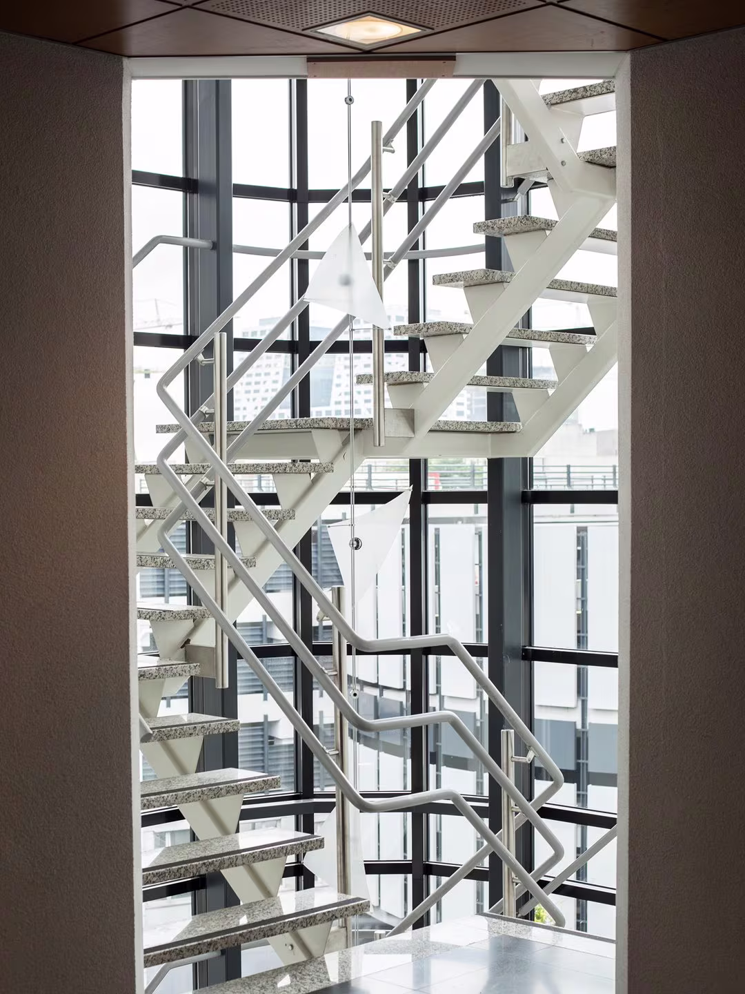 Modern trappenhuis met metalen trappen en glazen wanden in een kantoorgebouw met uitzicht op de stad.