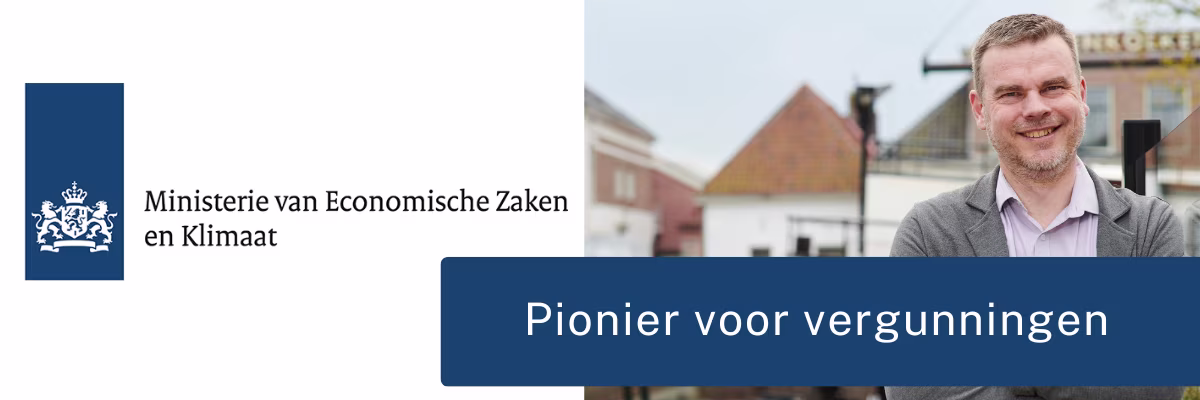 Een lachende man in grijze trui staat buiten in een stad, naast het logo van het Ministerie van Economische Zaken en Klimaat.