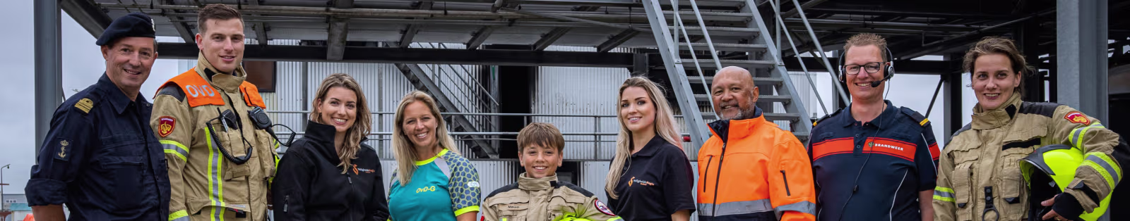 Groepsfoto van medewerkers van Veiligheidsregio Zeeland in werkkleding en uniformen bij een brandweerkazerne.