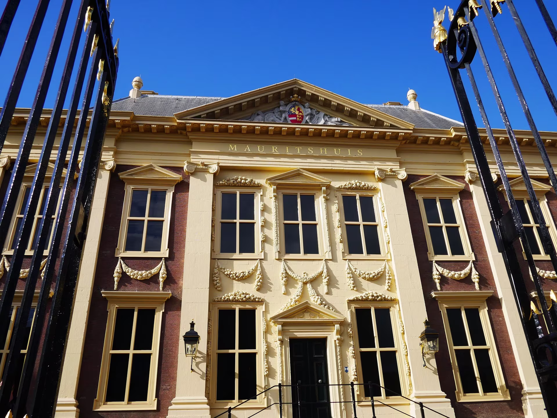 Voorkant van het Mauritshuis museum met klassieke gevel en gouden details, gefotografeerd vanaf een historisch schip.