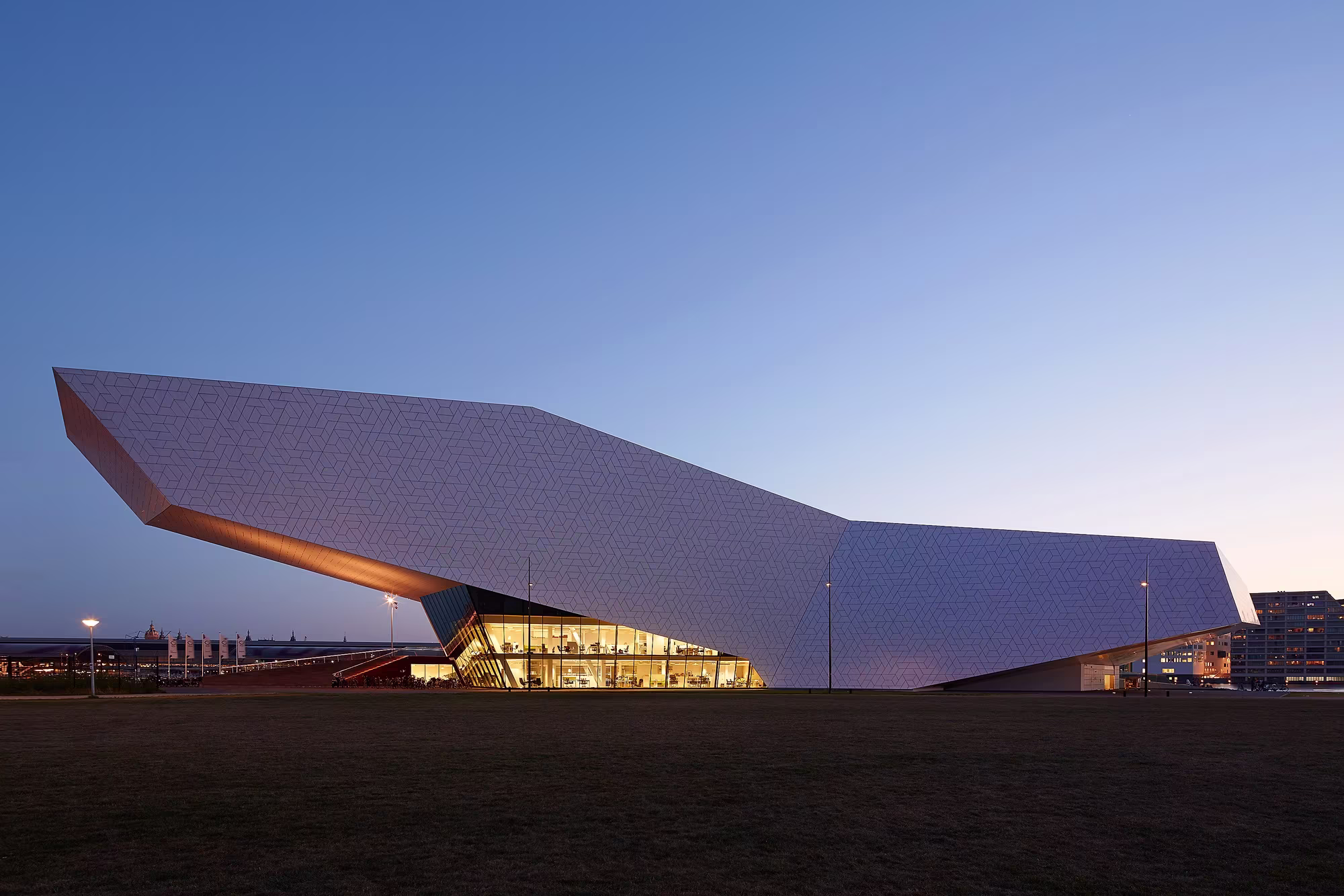 Het futuristische Eye Filmmuseum in Amsterdam bij schemering, met zijn opvallende witte gebogen architectuur verlicht tegen de avondlucht.