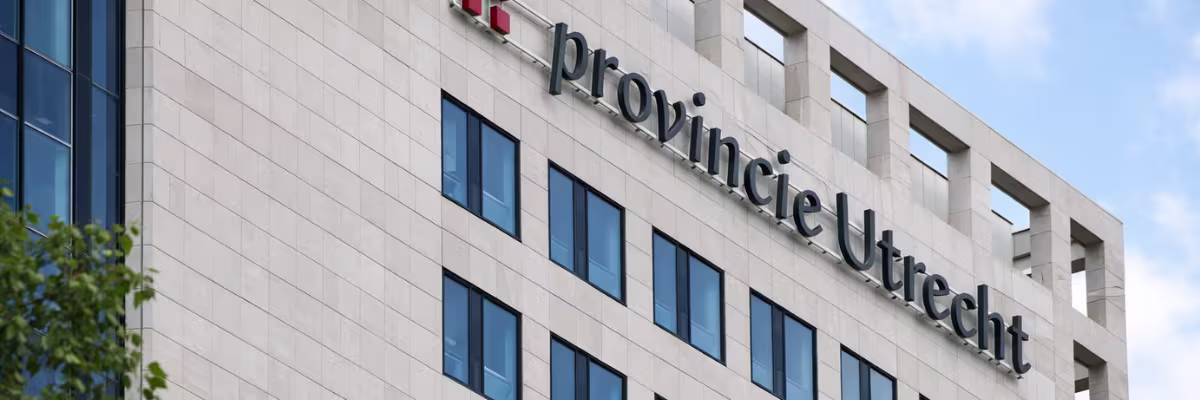 Modern kantoorgebouw van Provincie Utrecht met grote letters op de gevel onder blauwe hemel.