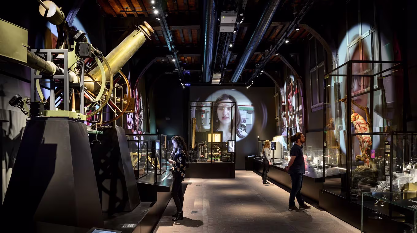 Moderne museumzaal met astronomische instrumenten, glazen vitrines en bezoekers die rondkijken tussen de tentoongestelde objecten.