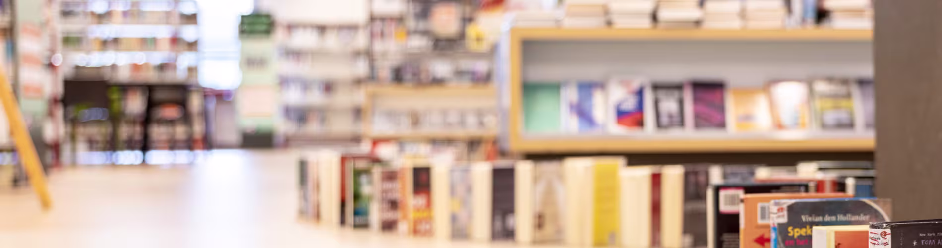 Boekenplanken en collectie in een bibliotheek met warme verlichting en overzichtelijke indeling.