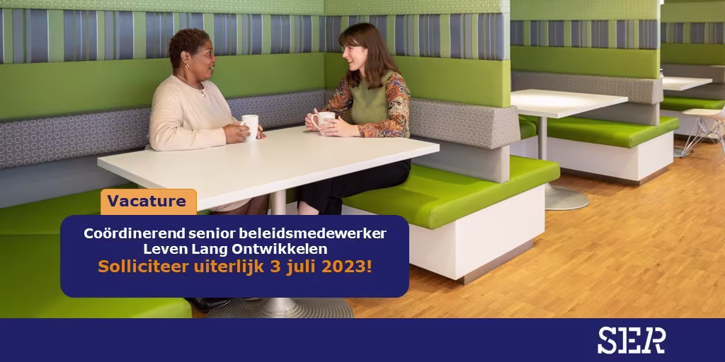 Twee vrouwen voeren een gesprek aan een witte tafel in een moderne kantooromgeving met groene en grijze zitmeubels.