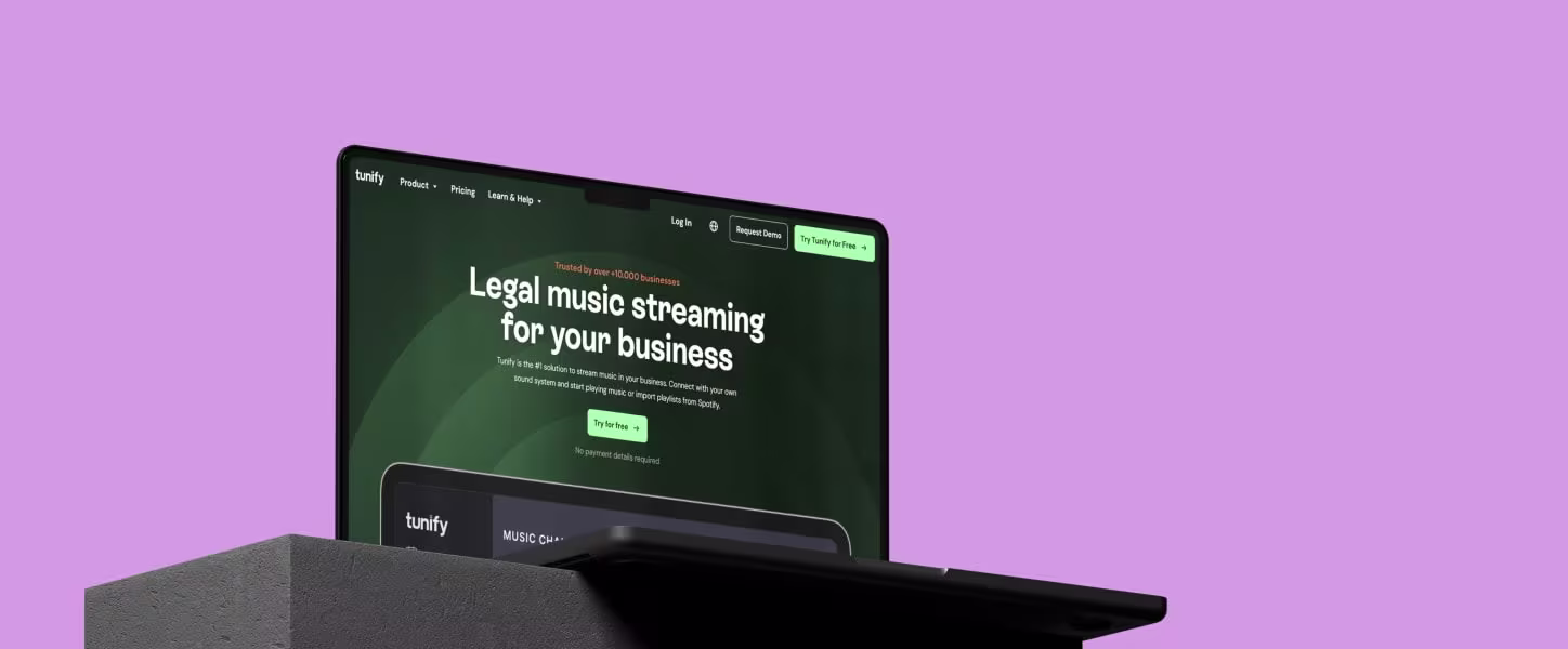 Een laptop toont de website van Tunify met de tekst "Legal music streaming for your business" op een paarse achtergrond.