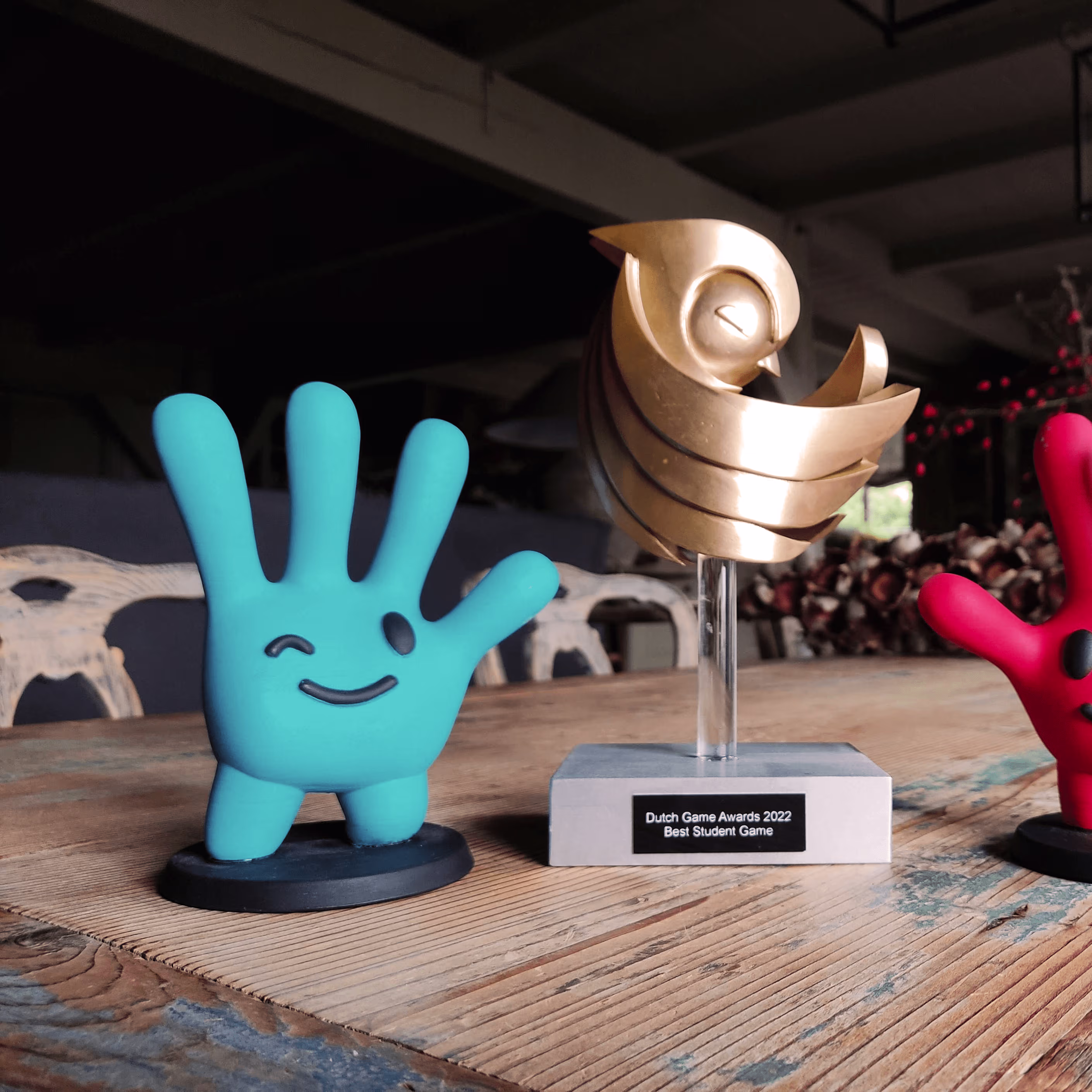 Een award van de Dutch Game Awards 2022 voor Best Student Game staat naast twee kleurrijke speelgoedfiguren op een houten tafel.