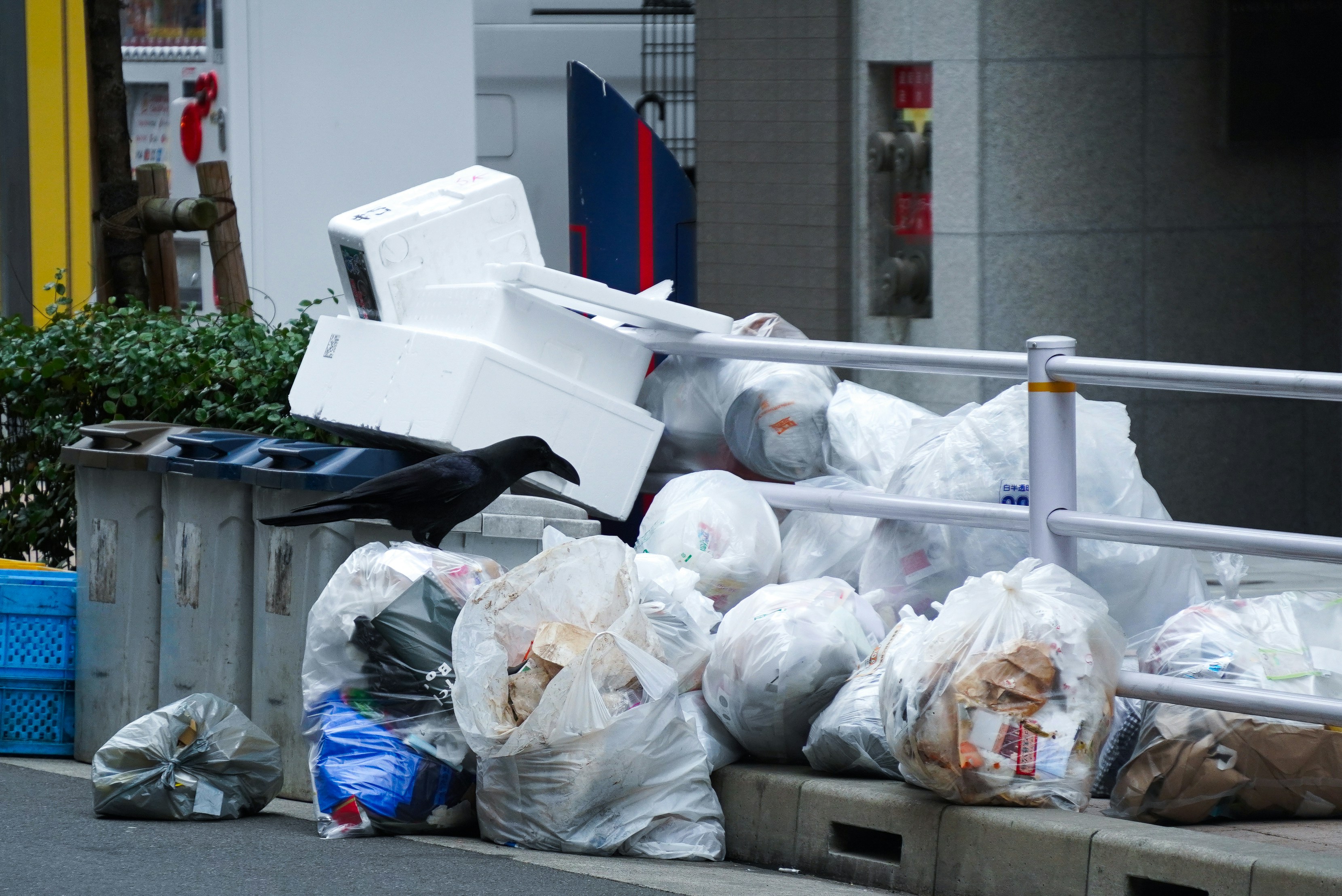 Large pile of waste bags and discarded packaging on a street outside a commercial premises