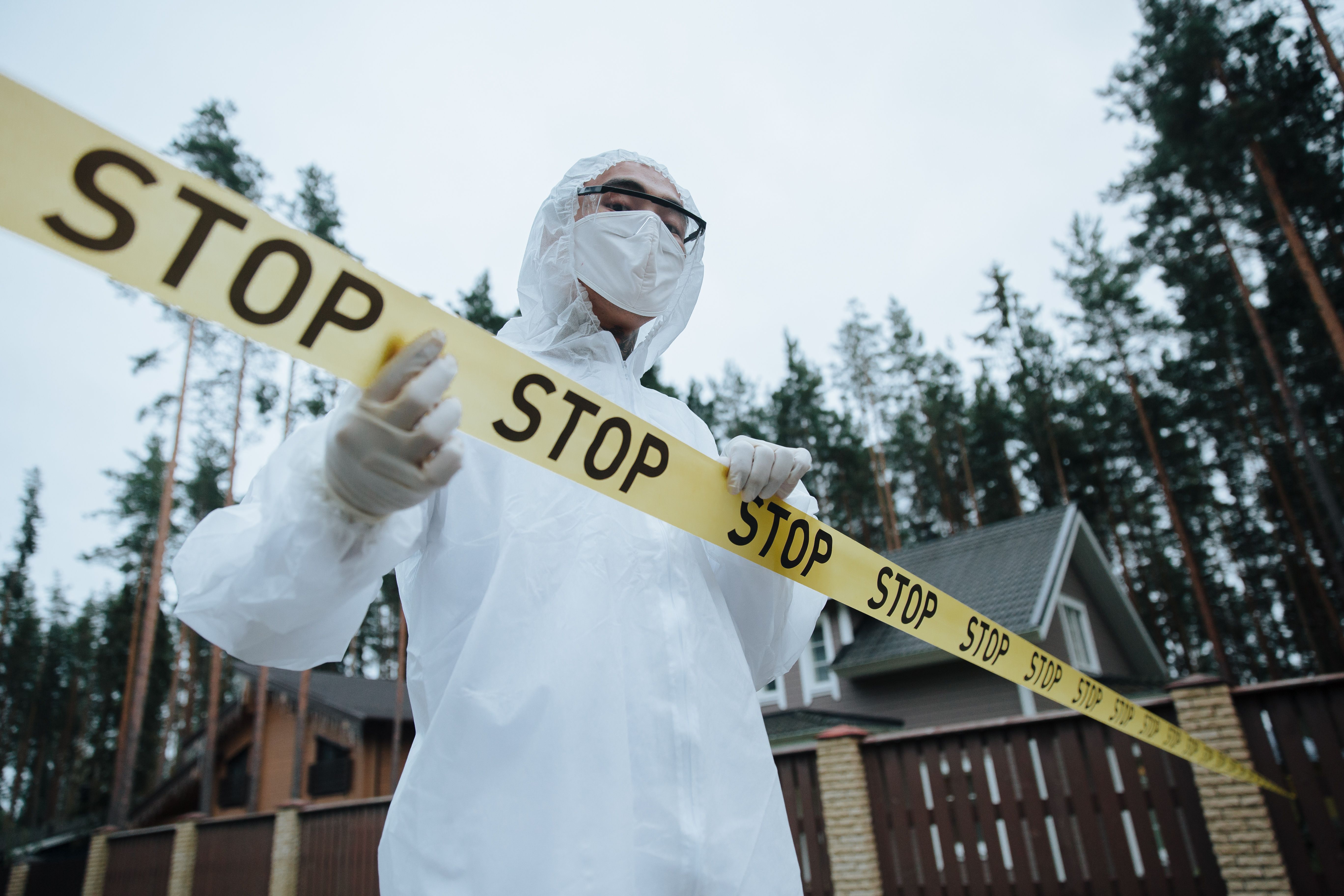 Hazmat technician securing an area with yellow barrier tape.