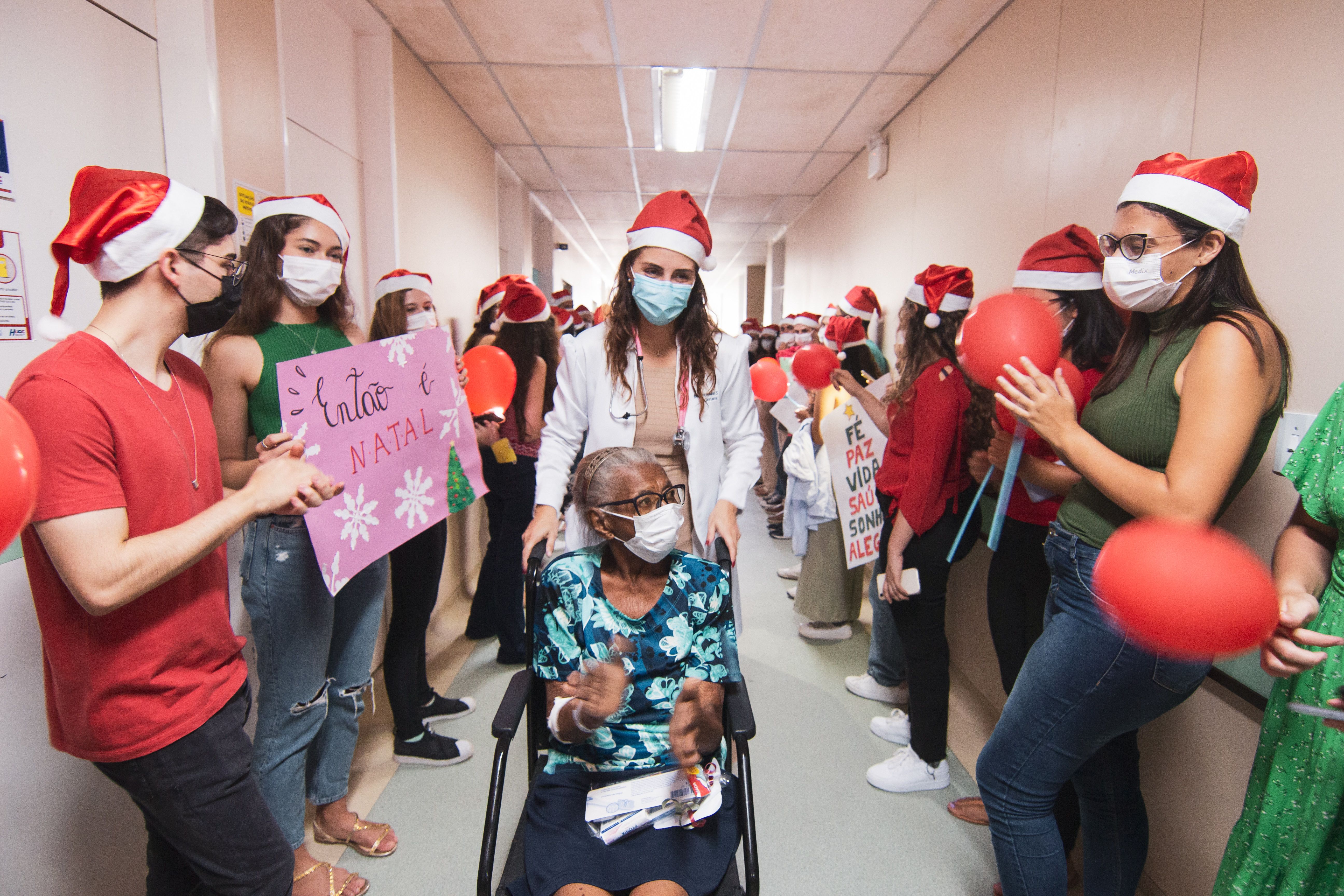 Elderly hospital patient in a wheelchair being supported by a healthcare worker