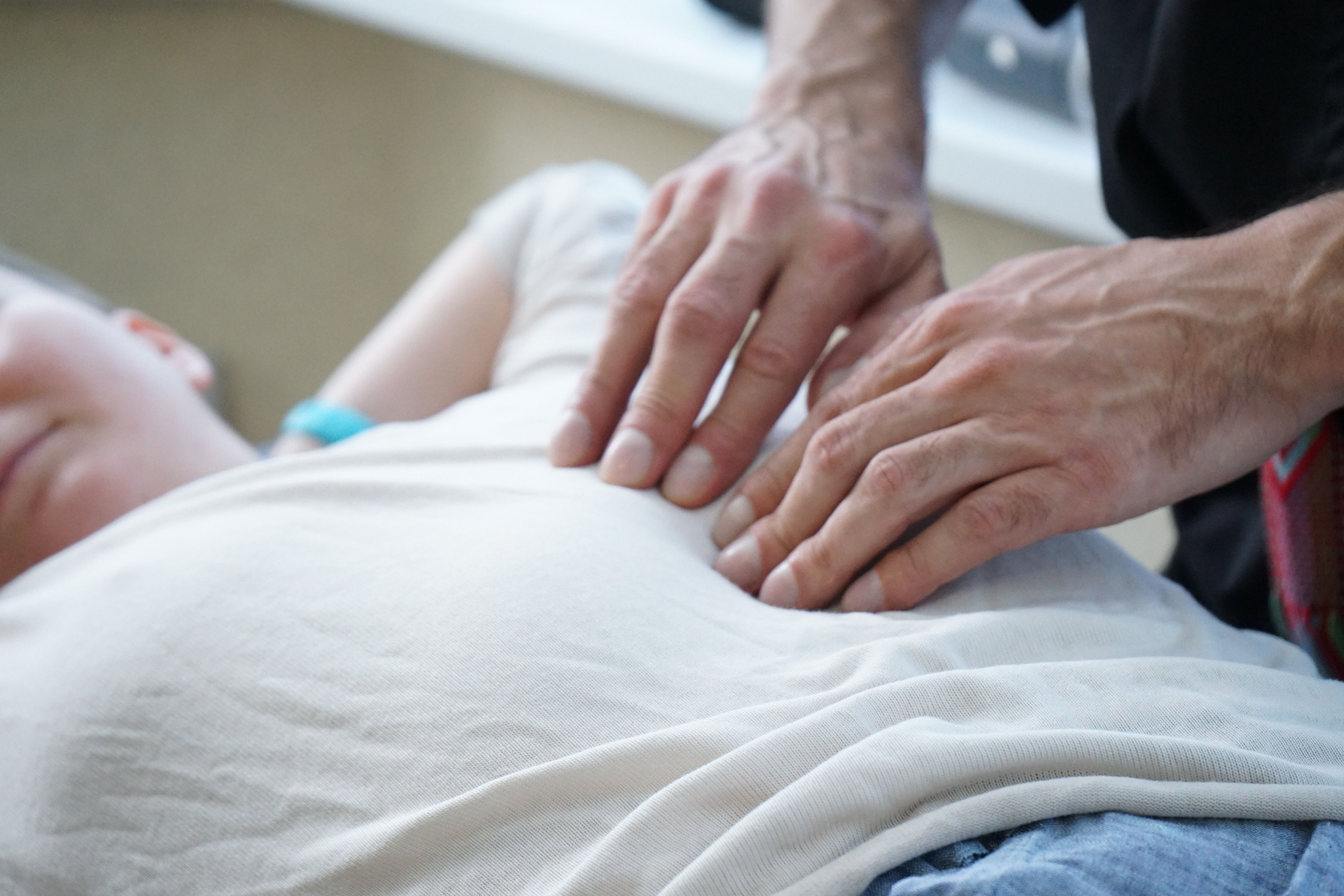 Medical practitioner examining a patient's abdomen during a physical checkup.
