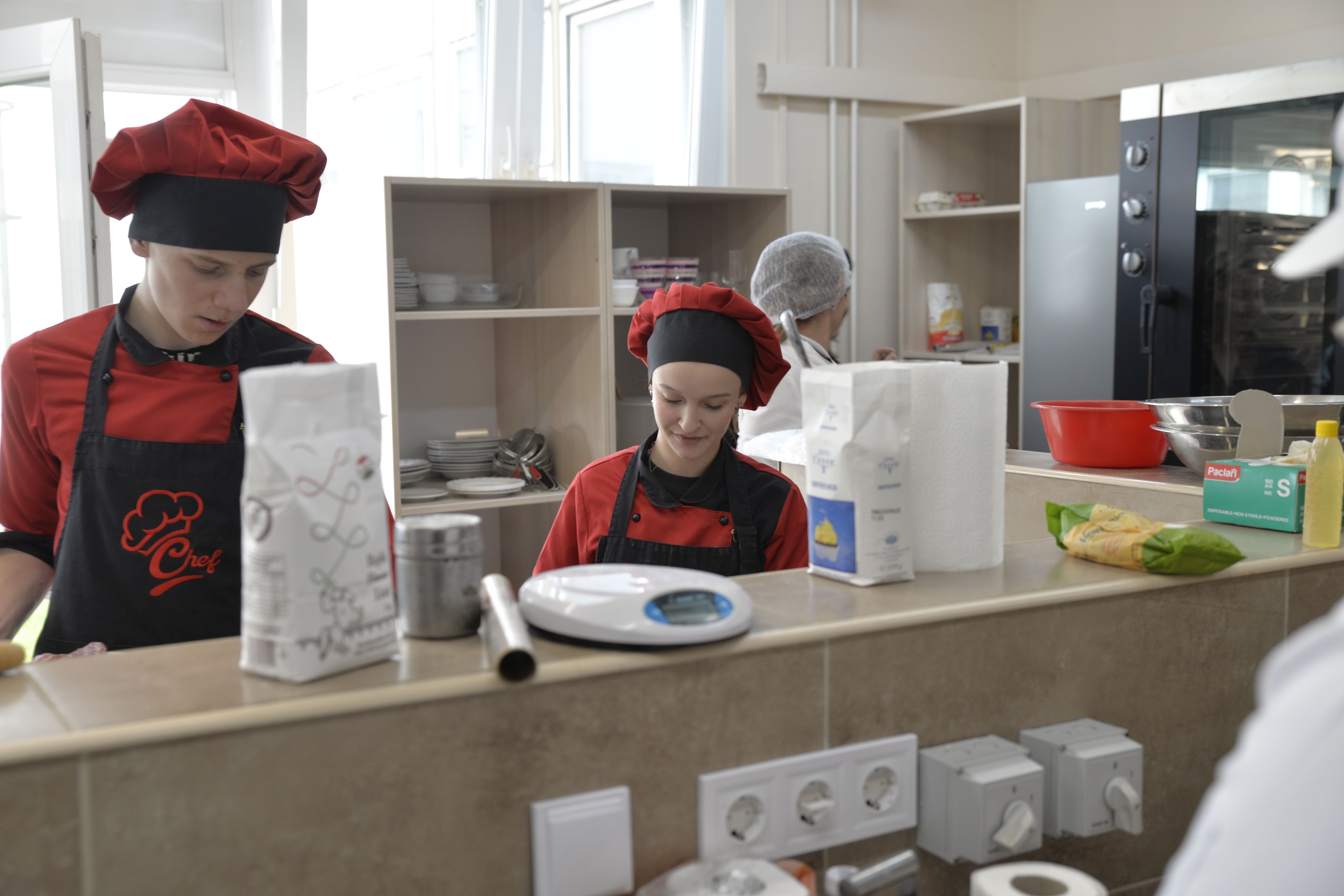 Bakery staff measuring ingredients in a clean commercial kitchen setting.