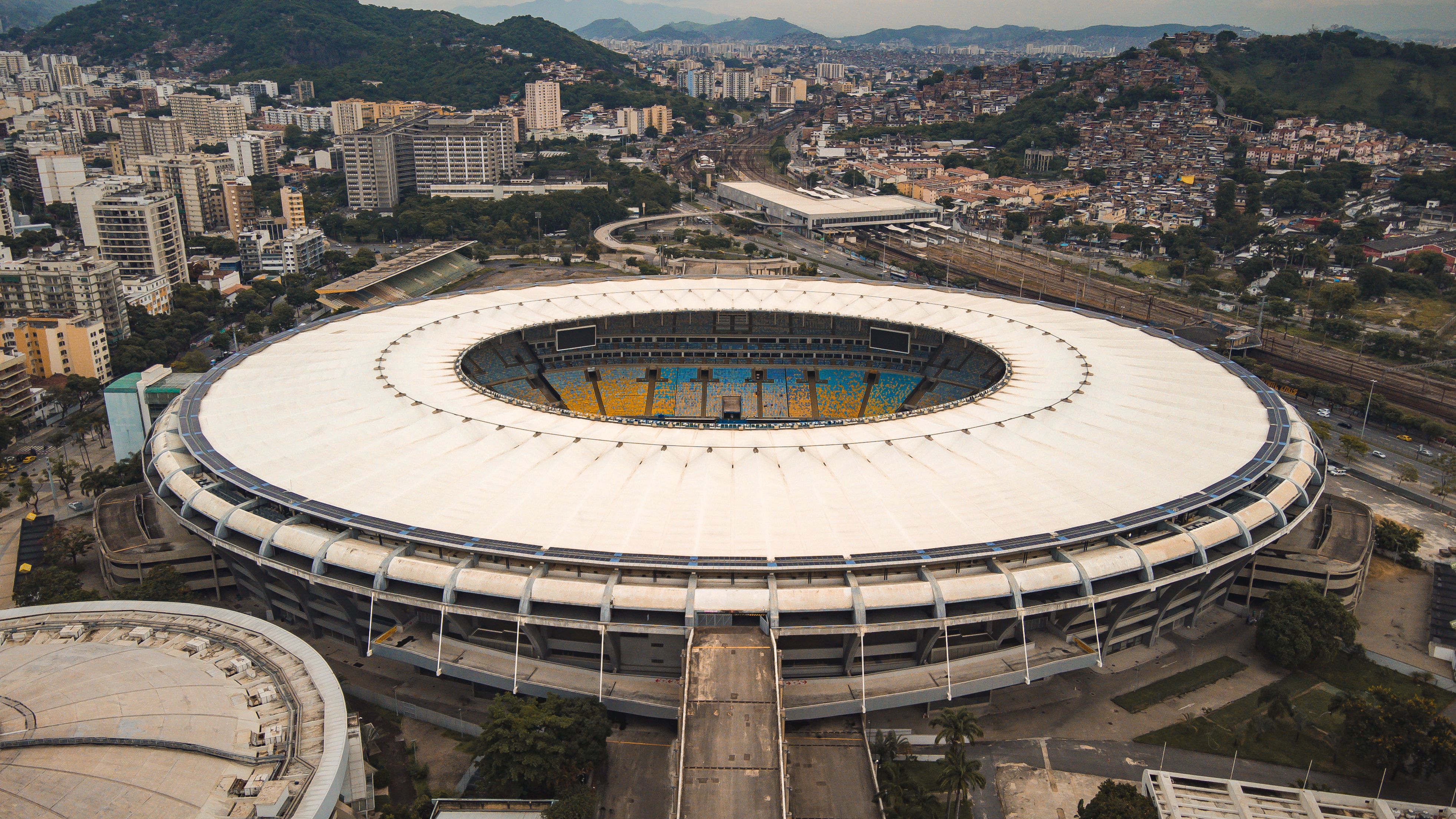 High-angle aerial view of a massive circular sports stadium surrounded by an urban city landscape