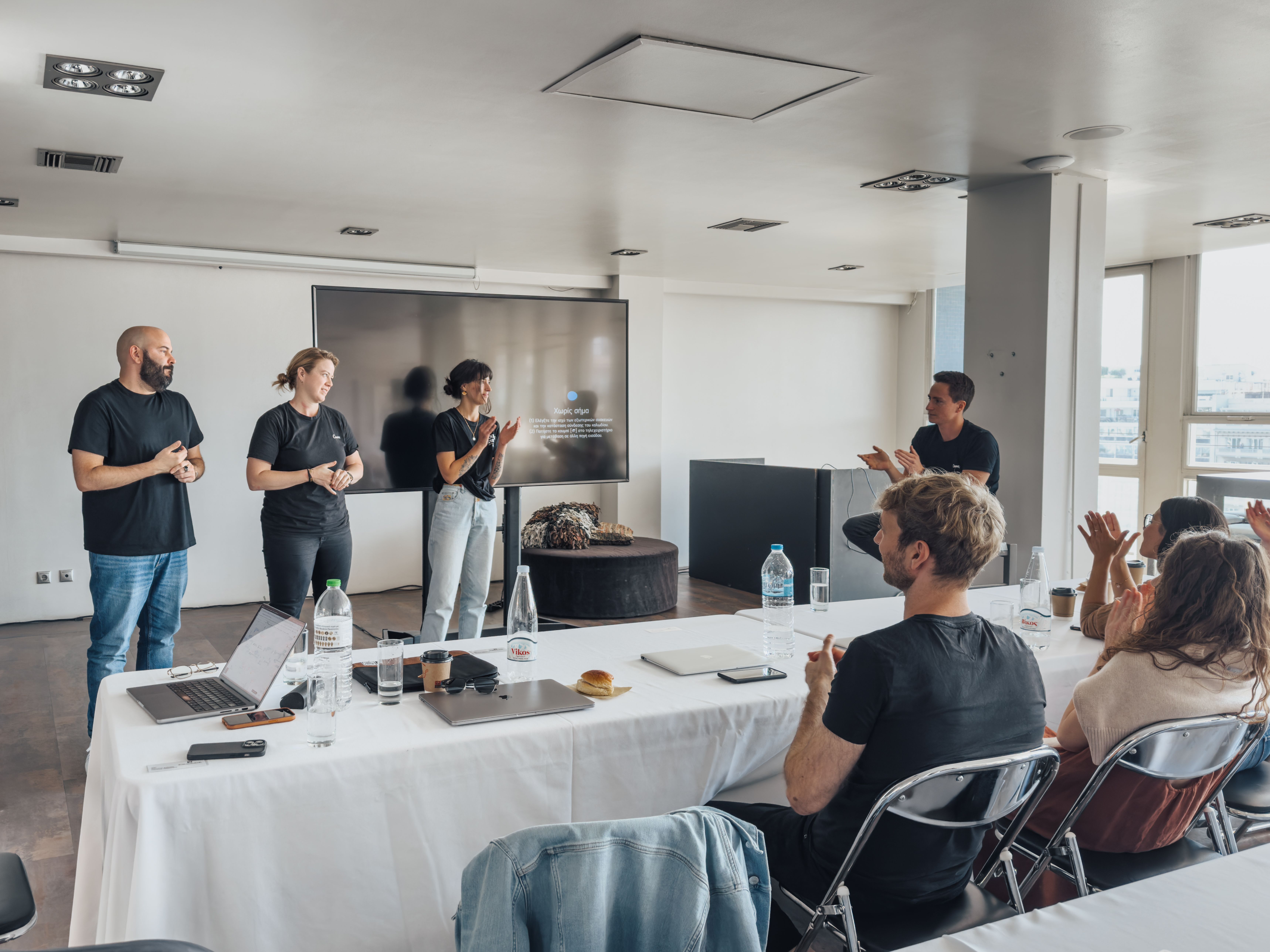 Presenters leading a training session and presentation in a conference room while participants applaud.