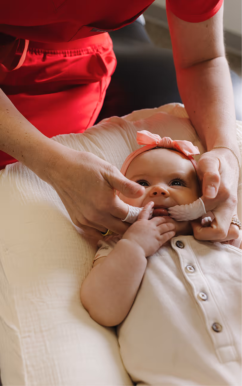 A woman is holding a baby in her lap.