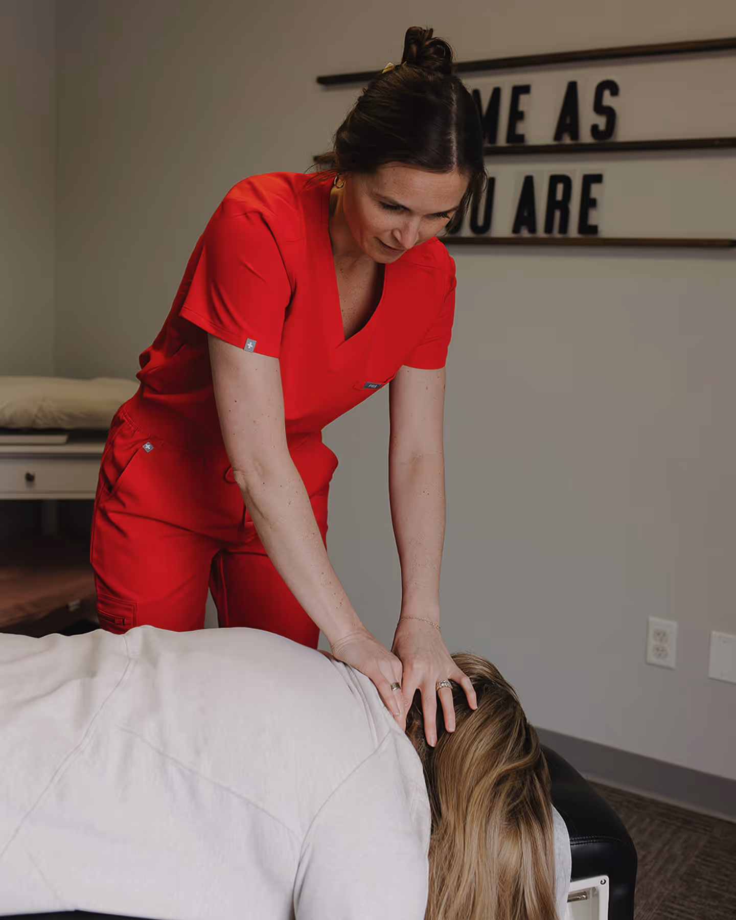 A woman getting a back massage from a woman in a red shirt.