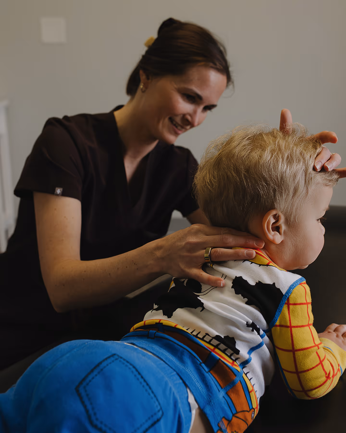 A woman is combing a young boy's hair.