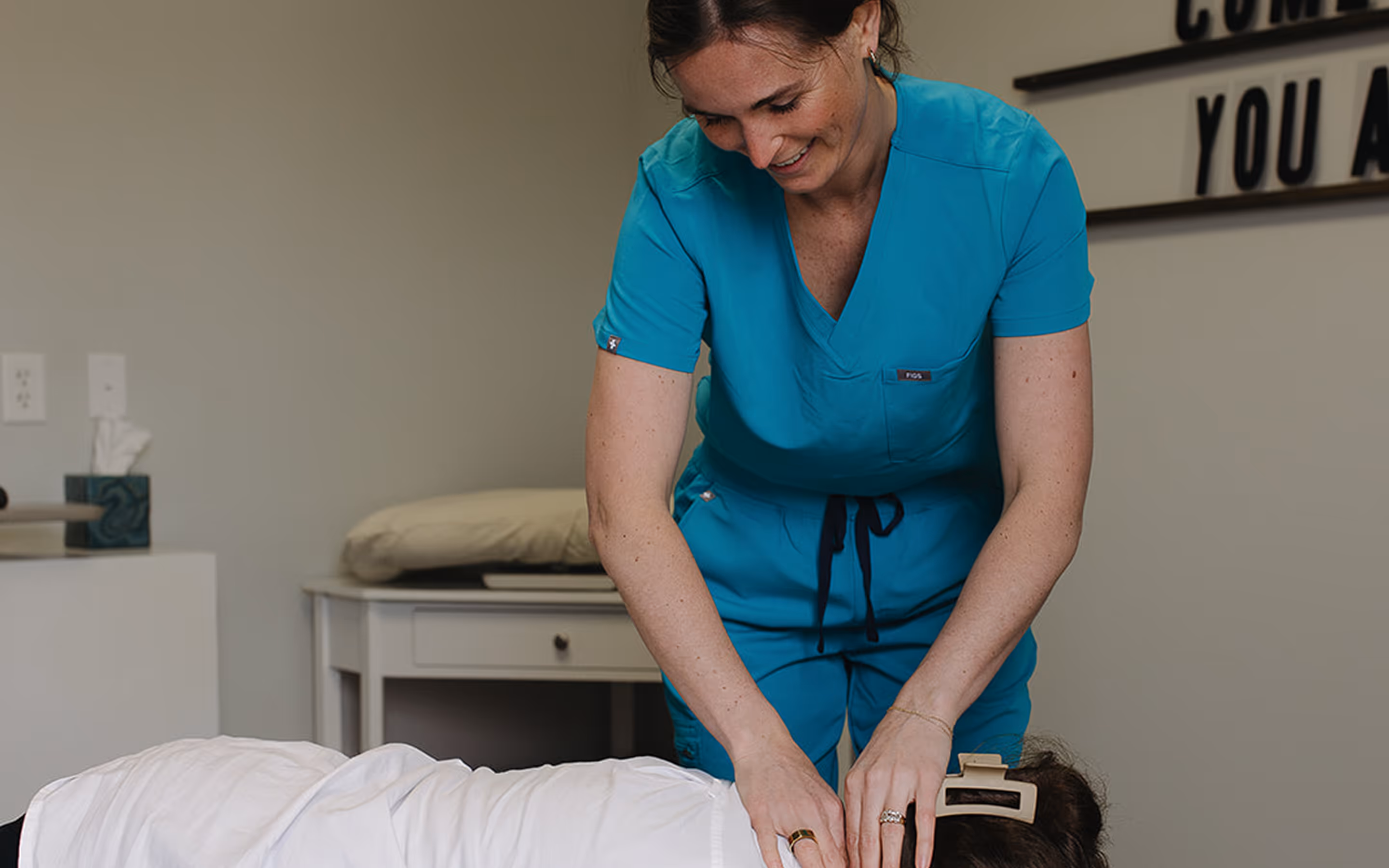 A woman in scrubs is doing a back massage.