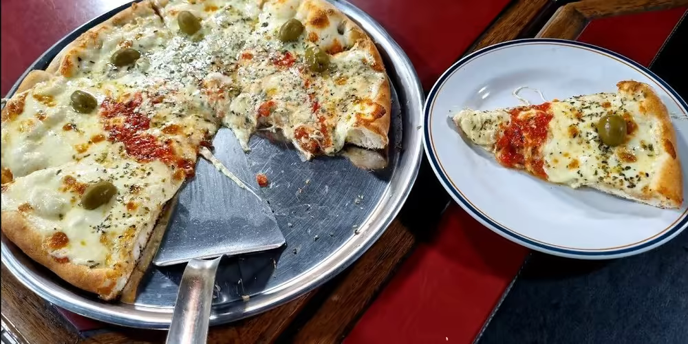 Pizza argentina completa de muzzarella y aceitunas sobre bandeja