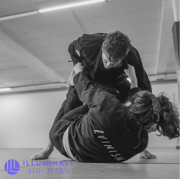Two people practicing Brazilian Jiu-Jitsu in Regensburg, one person on the ground gripping the other's gi while the other leans forward.