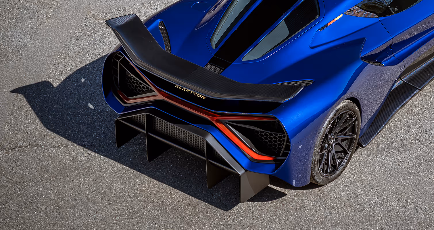 Close-up of a blue sports car's rear wheel with Michelin tire and black alloy rim featuring a yellow brake caliper.